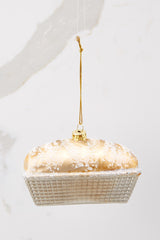 Side view of this ornament that features a gold and glitter encrusted tin of bread. 