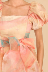 Close up view of this dress that features puffed sleeves, a square neckline, and a tie around the waist.