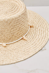 Close up view of this hat that features a shell lining and a strap with seashell detail.