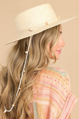 Side view of this hat that features a shell lining and a strap with seashell detail.