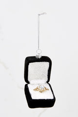 This engagement ring ornament features a black box, white sparkly inside, and a gold ring.