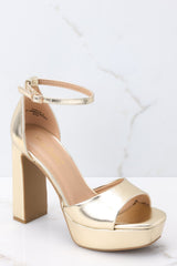 Outer-side view of these shoes that feature an adjustable ankle strap, a gold strap over the foot, a chucky heel, and a platform style. 