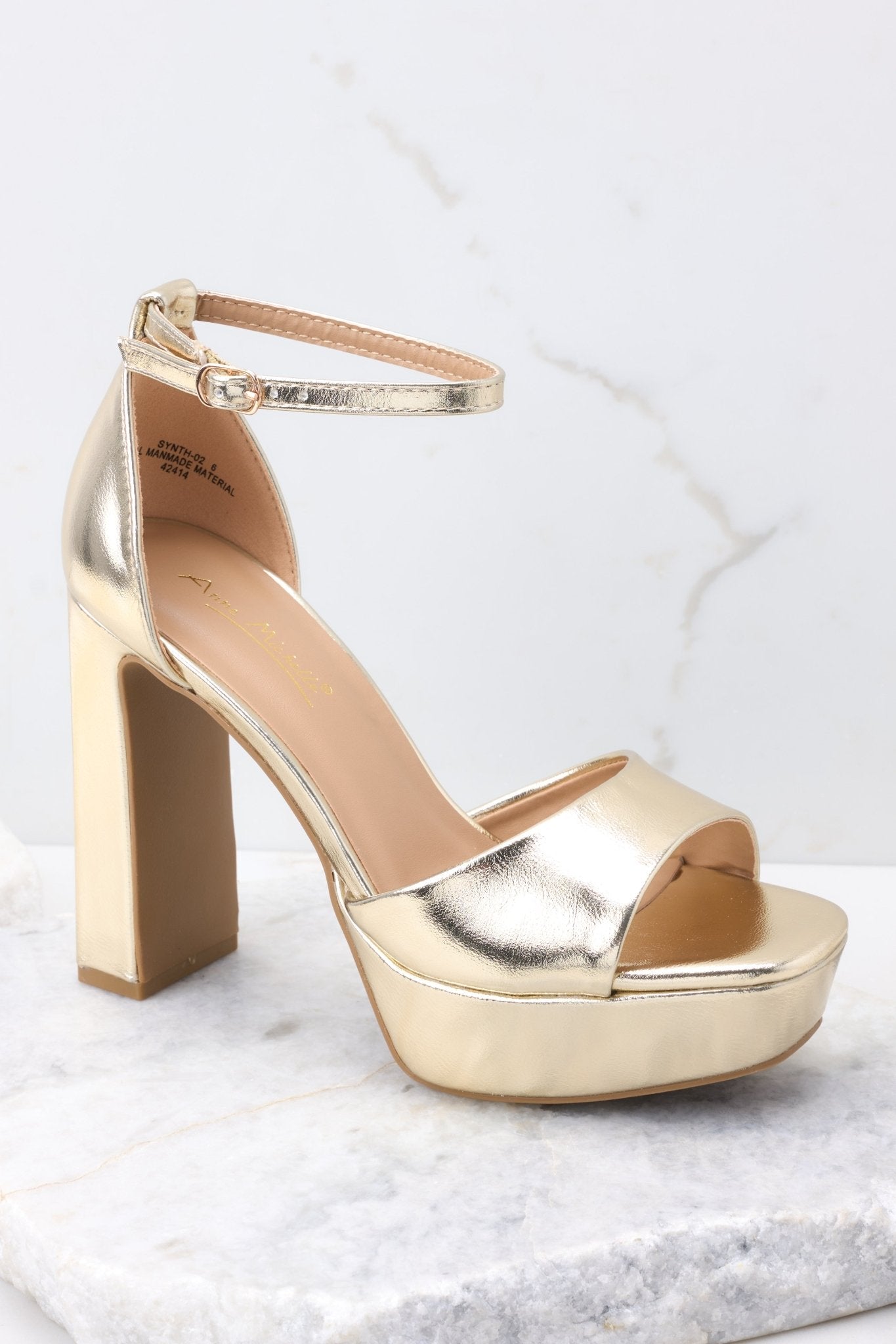 Close up view of these shoes that feature an adjustable ankle strap, a gold strap over the foot, a chucky heel, and a platform style. 