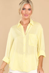 This yellow top features a collared neckline, functional buttons down the front, a functional pocket at the bust, buttoned cuffs, and a flowy material.