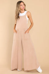 Front view of this jumpsuit that features a square neckline, non-adjustable straps, an open back, an elastic band at the back of the waist, functional front pockets, and a flowy, wide leg design.