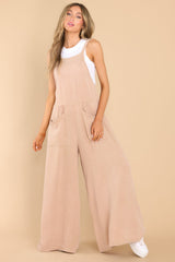Full body view of this jumpsuit that features a square neckline, non-adjustable straps, an open back, an elastic band at the back of the waist, functional front pockets, and a flowy, wide leg design.