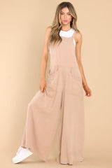 Full body view of this jumpsuit that features a square neckline, non-adjustable straps, an open back, an elastic band at the back of the waist, and a flowy, wide leg design.