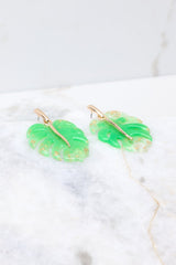 Side view of these tropical earrings that feature a leaf design with gold flecks set into acrylic, and gold hardware.