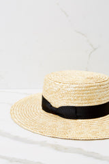 Close up view of this boater hat that features a natural straw structured brim, a black bow detail gross-grain ribbon, and natural straw.