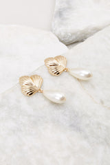 These earrings feature a seashell stud base, secure post backing, and oval, pearl dangles.