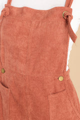 Close up view of these overalls that feature adjustable self-tie straps, four functional side pockets and two back pockets, buttons below the bust to allow for a folded look, and a corduroy texture throughout.