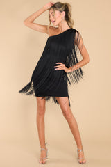 This all black dress features a one shoulder design, functional zipper on the side, and fringe detailing throughout with lots of movement.