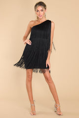 Full body view of this dress that features a one shoulder design, functional zipper on the side, and fringe detailing throughout with lots of movement.