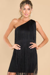 Front view of this dress that features a one shoulder design, functional zipper on the side, and fringe detailing throughout with lots of movement.