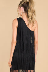 Back view of this dress that features a one shoulder design, functional zipper on the side, and fringe detailing throughout with lots of movement.