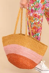 This natural, pink, and orange bag features  a woven colorblock design and woven handles. 