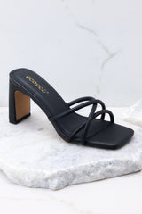 These black sandals feature a textured black finish, three straps across the top of the foot, a flattened block heel, and light cushioning in the base.
