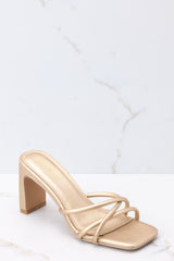 These champagne colored sandals feature a textured gold finish, three straps across the top of the foot, a flattened block heel, and light cushioning in the base. 