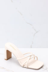 These ivory sandals feature a textured ivory-colored finish, three straps across the top of the foot, a flattened block heel, and light cushioning in the base.