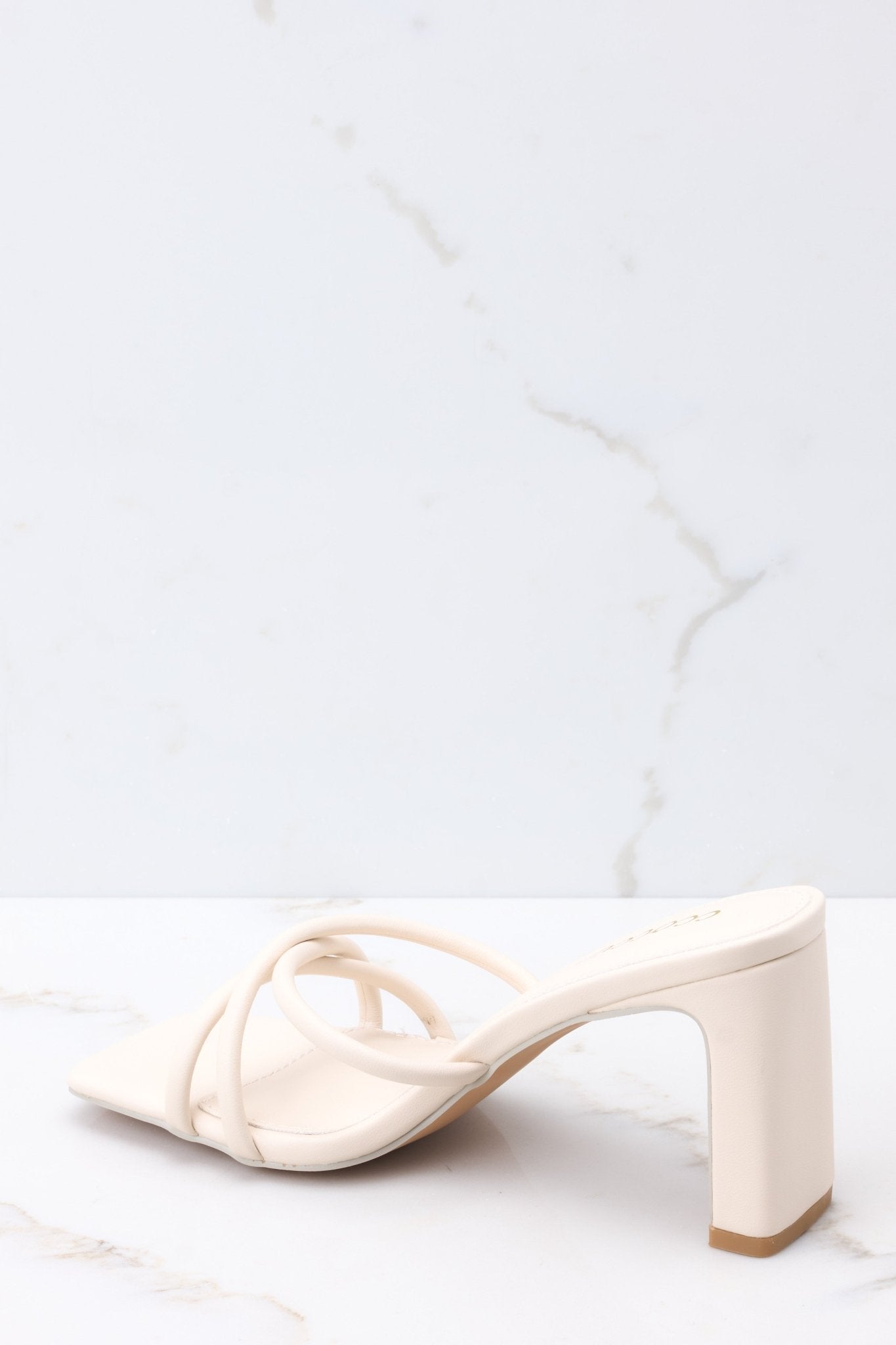 Inner-side view of these sandals that feature a textured ivory-colored finish, three straps across the top of the foot, a flattened block heel, and light cushioning in the base.