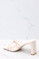 Inner-side view of these sandals that feature a textured ivory-colored finish, three straps across the top of the foot, a flattened block heel, and light cushioning in the base.