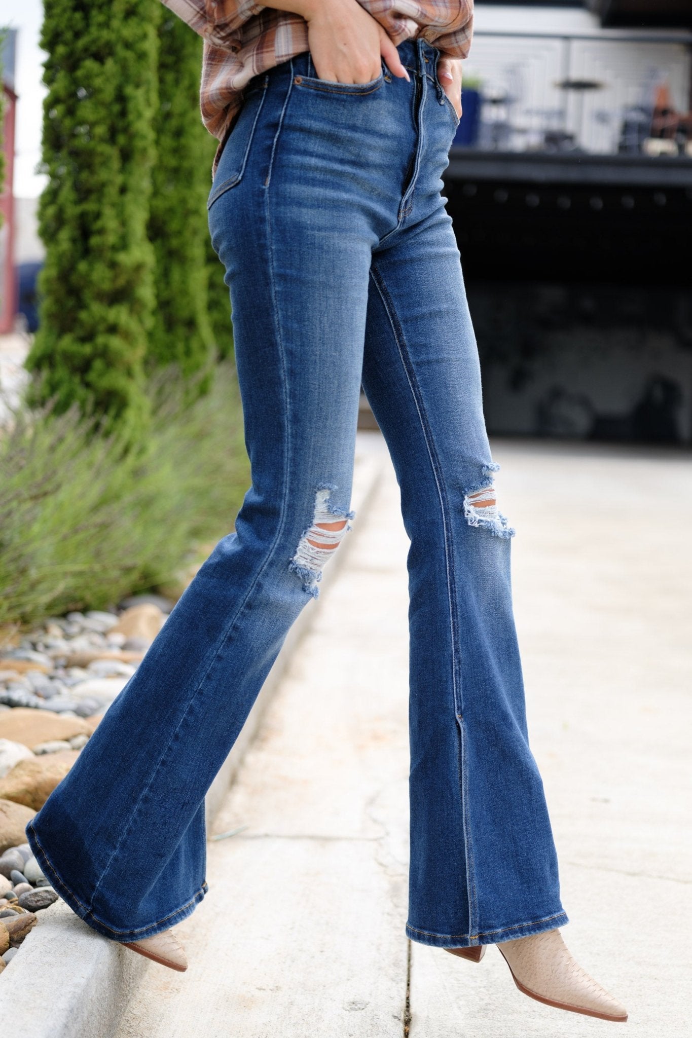 Side view of these jeans that feature  light distressing throughout, wide legs, functional pockets, and a standard zipper and button closure.