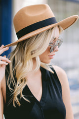 This tan wide brimmed hat features a black ribbon band.