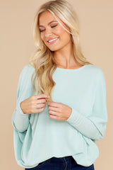 Front view of this pull over top that features a round neckline, long dolman sleeves, and a slight high low hem line.