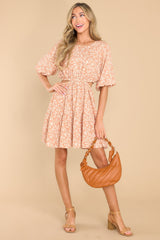 Full body view of this dress that showcases the white floral print of the camel colored fabric.