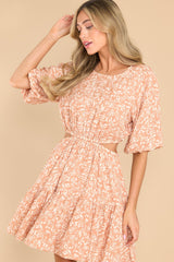 This camel colored dress features a round neckline, functional buttons down the back, puff sleeves with elastic cuffs, a cutout around the waist with two elastic bands, and a flowy skirt.