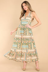 This green and tan dress features a v-neckline, pleated detailing at the waist, and a wide, flowy skirt.