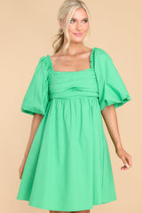Front view of  this dress that features a square neckline, puff sleeves with elastic cuffs, pleated detail over bust, and flowy skirt.