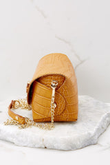 Side view of this bag that features a leather body, gold-colored hardware, wooden turn-lock closure, detachable curb chain strap that drops 23