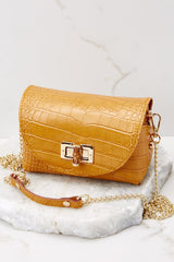 Front view of this bag that features a leather body, gold-colored hardware, wooden turn-lock closure, detachable curb chain strap that drops 23