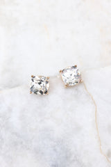 Detailed marble shot of gold earrings that feature square rhinestone studs and a secure post backing.