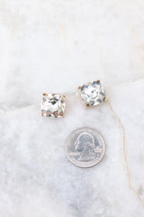 Gold rhinestone stud earrings compared to quarter for actual size. Earrings measure 0.25