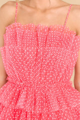 Close up view of this dress that features a square neckline, adjustable straps, a zipper down the back, and tulle ruffling with small white polka dots throughout.