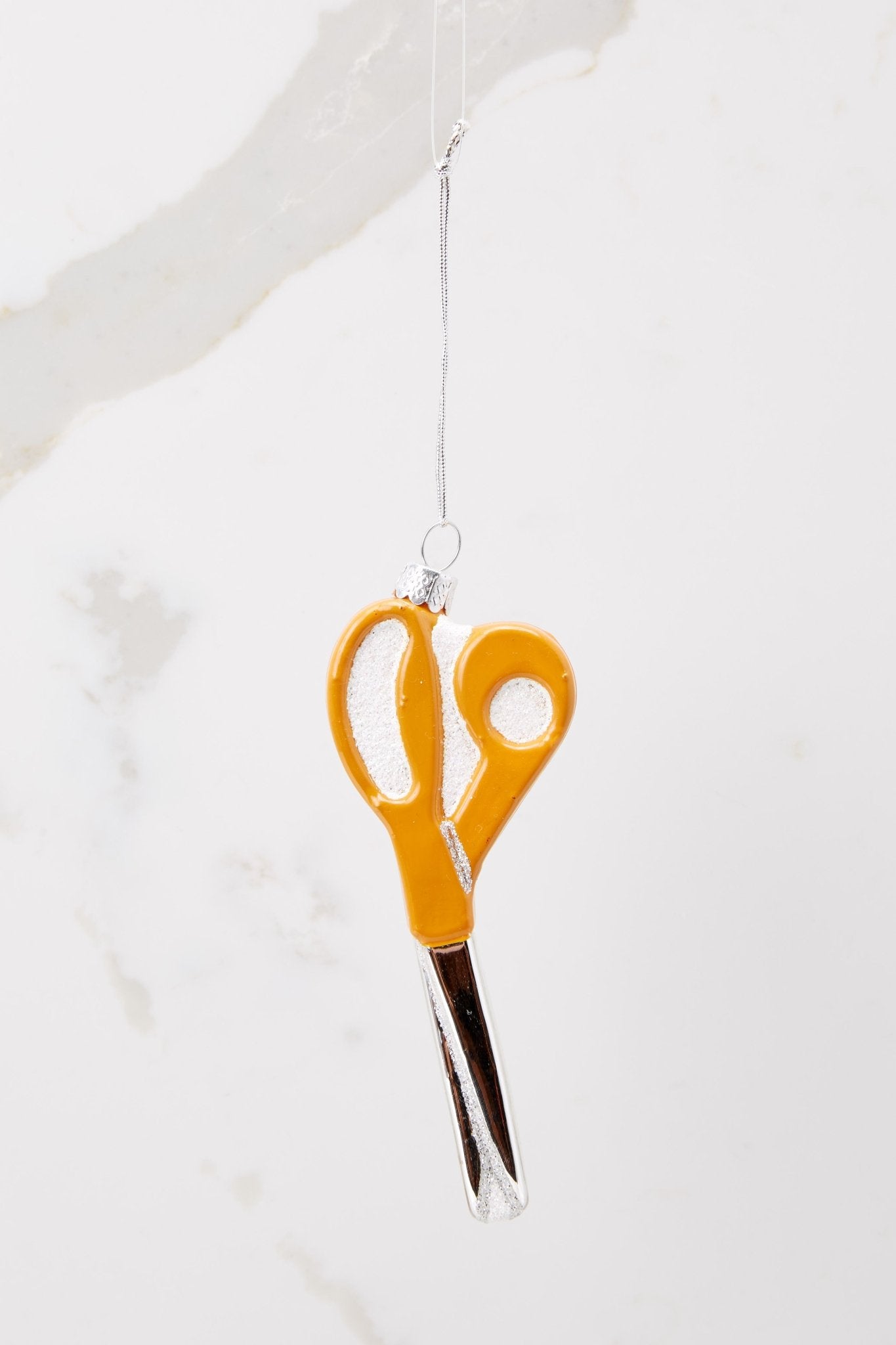 Back view of this ornament that features orange scissors.