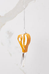 This orange and silver ornament features orange scissors.