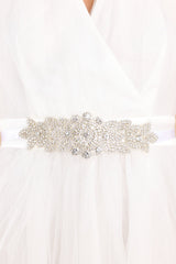 This silver belt features a crystal iridescent flower centerpiece, and a self-tie ribbon closure. 
