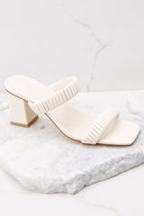 Outer-side view of these heels that feature a square toe, a slip on design, a thick heel and straps across the top of the foot.